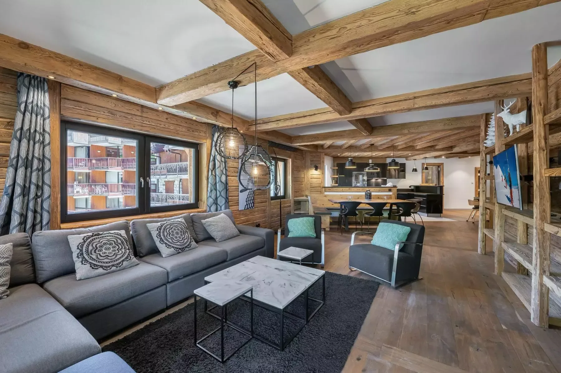 A spacious living area with seating, a coffee table, and exposed wooden beams.