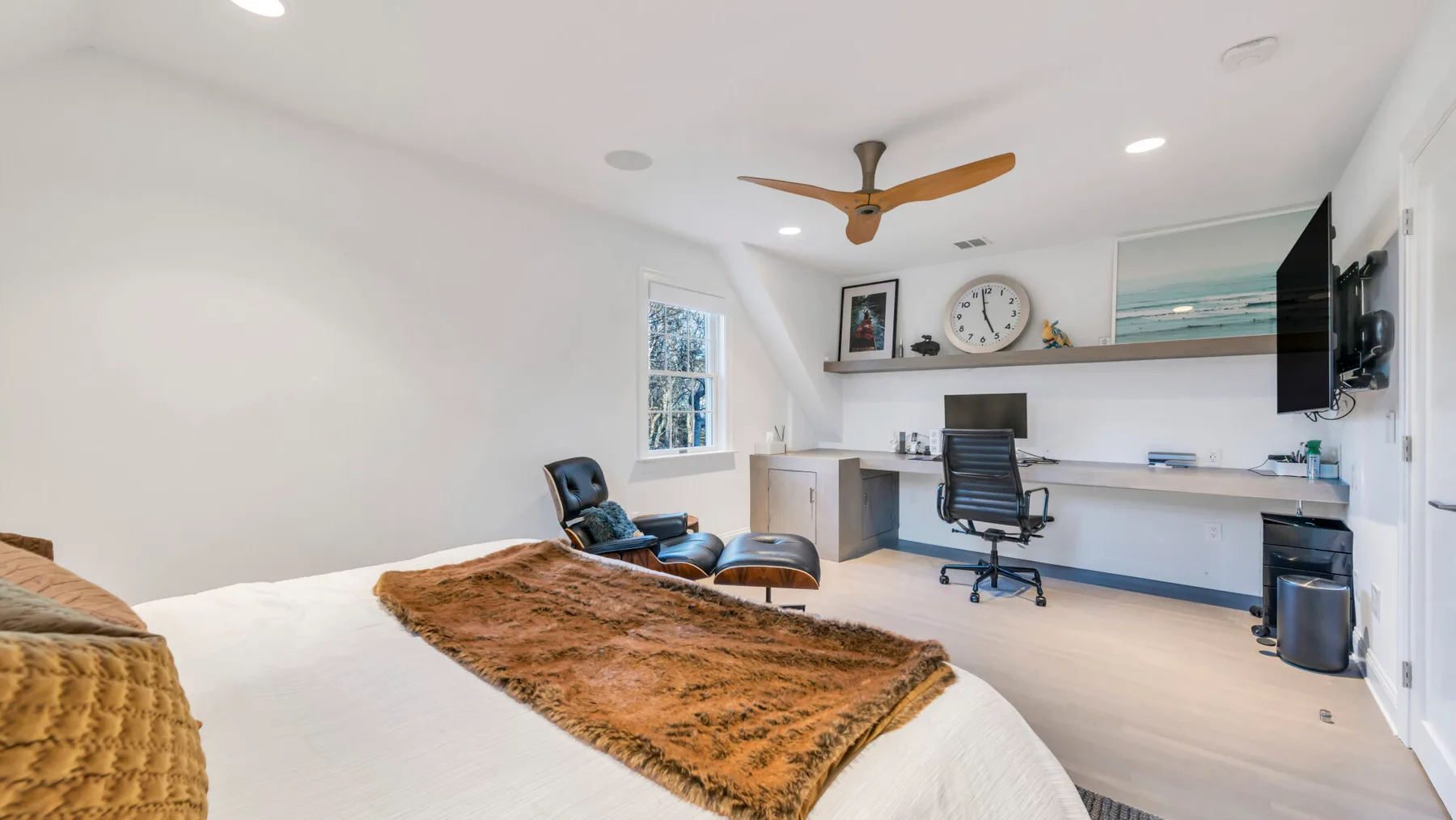 A bright bedroom with a bed, desk, and office chair.
