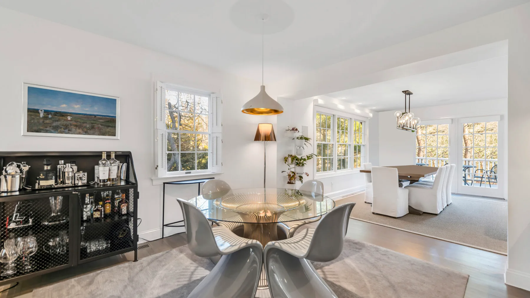 A bright dining area with a glass table and seating beside large windows.