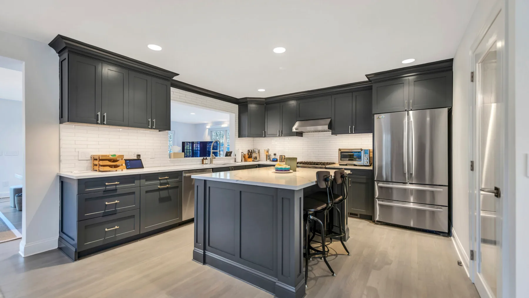 A modern kitchen with dark cabinets, stainless steel appliances, and a central island.