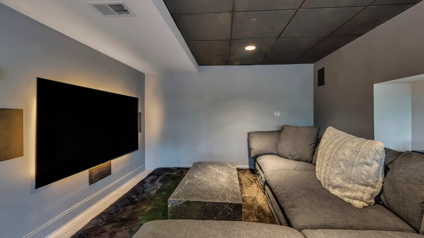 A living room with a large wall-mounted television and seating.