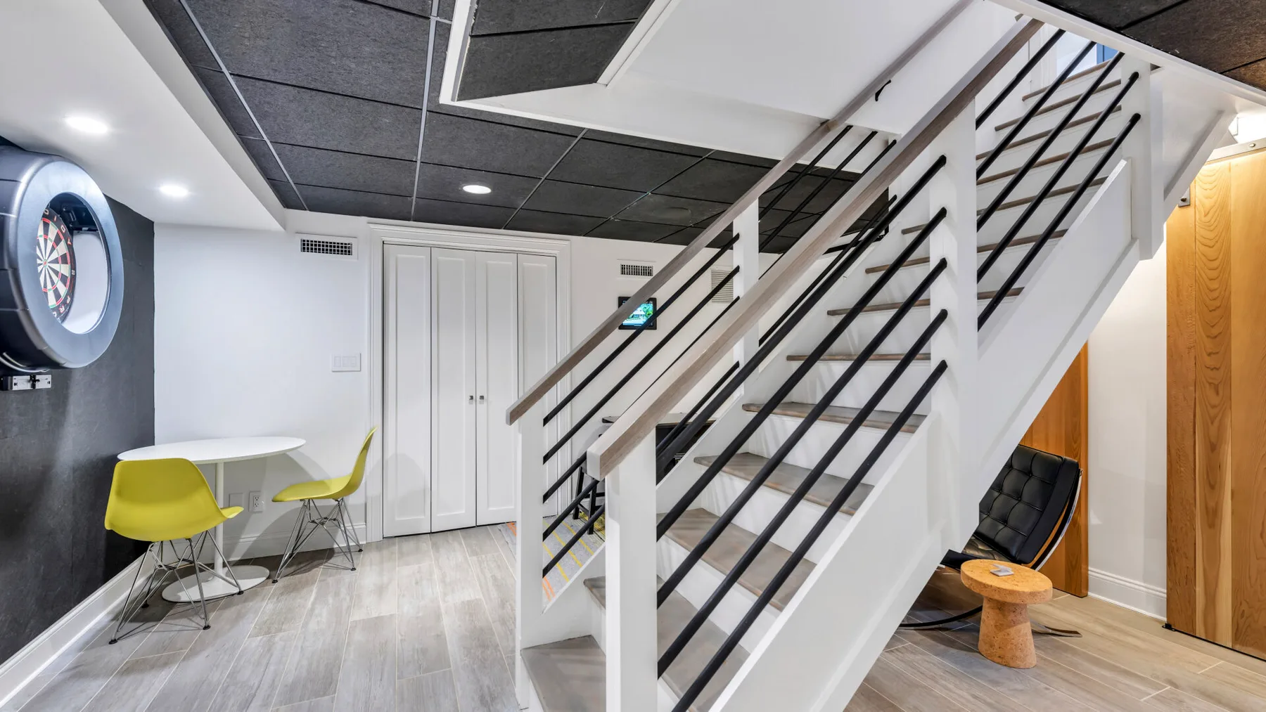 A modern interior with a staircase beside a small table and seating area.
