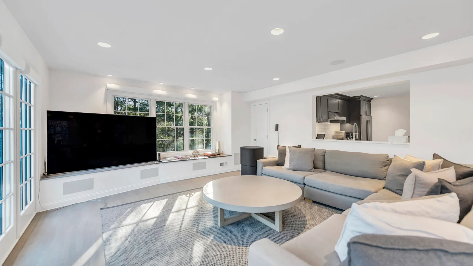 A bright living room with a large sectional seating area and a round coffee table.