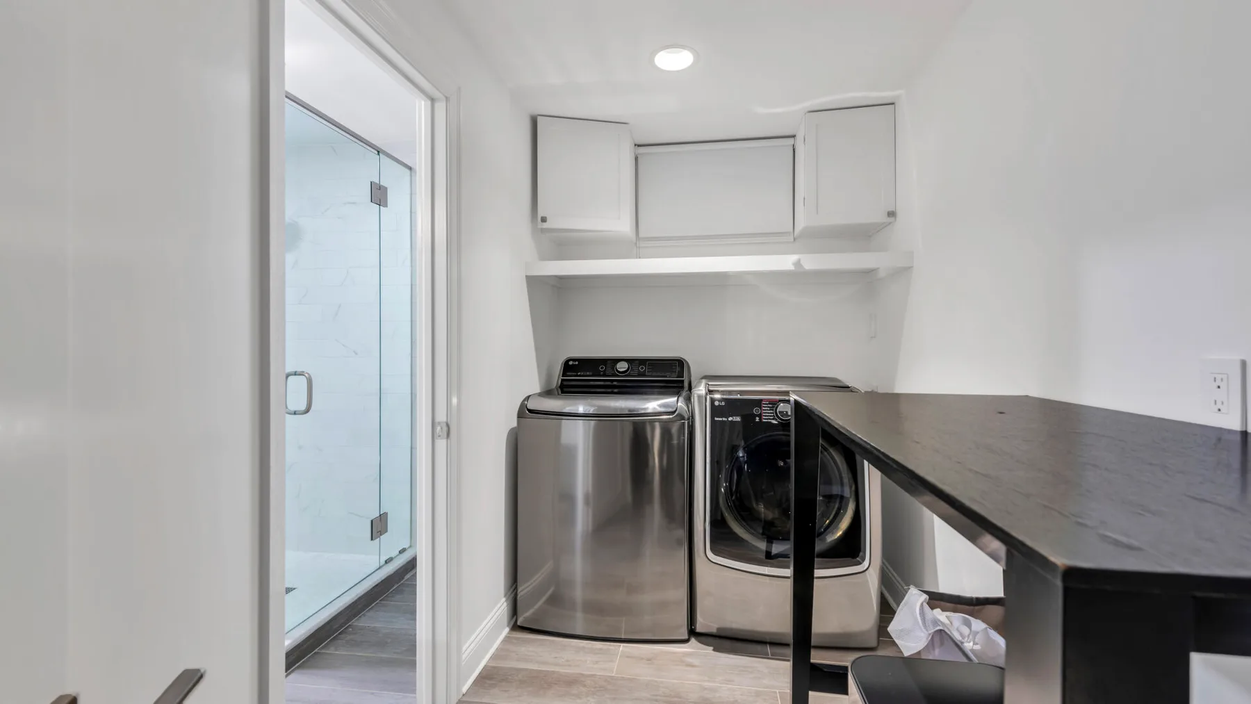 A laundry room with a washer, dryer, and dark countertop.
