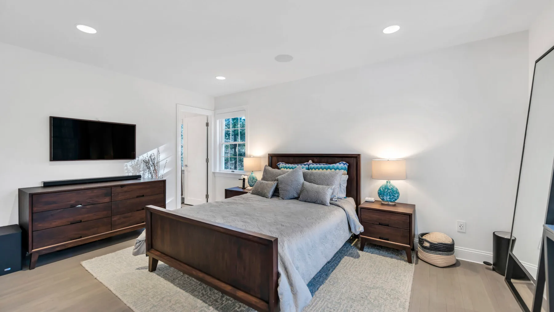 A bedroom with a bed, matching bedside tables, and a wall-mounted television.