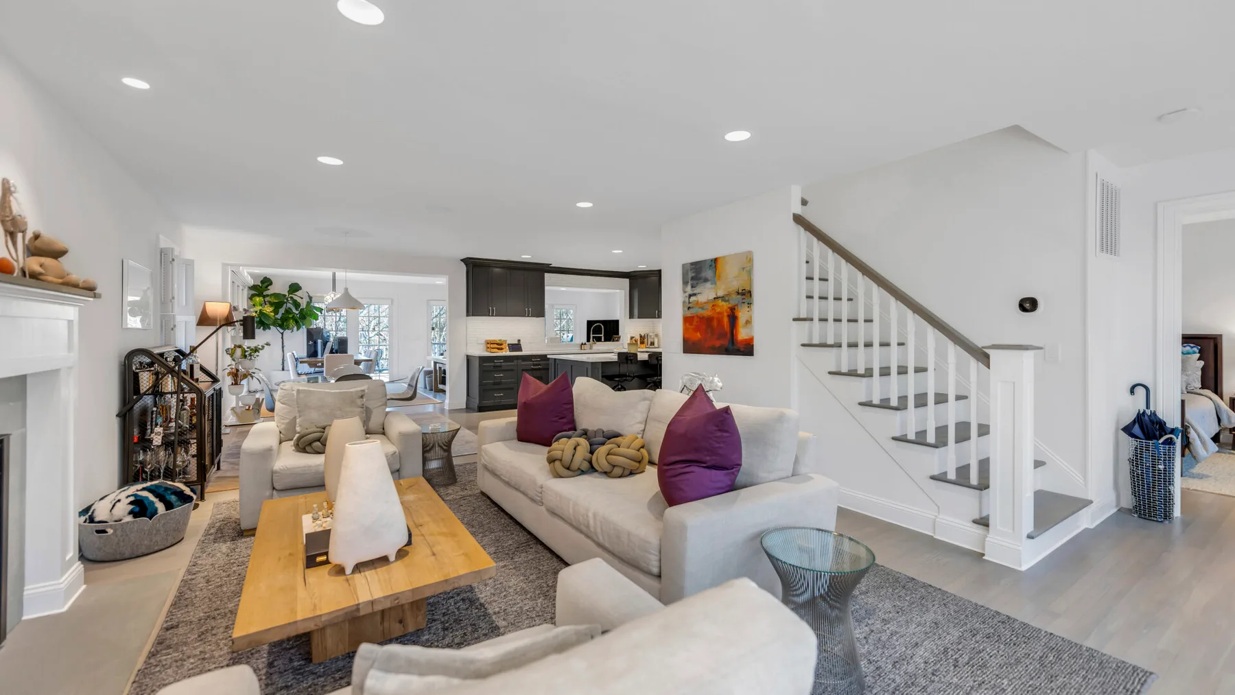 A bright living room with a sectional sofa, coffee table, and staircase.