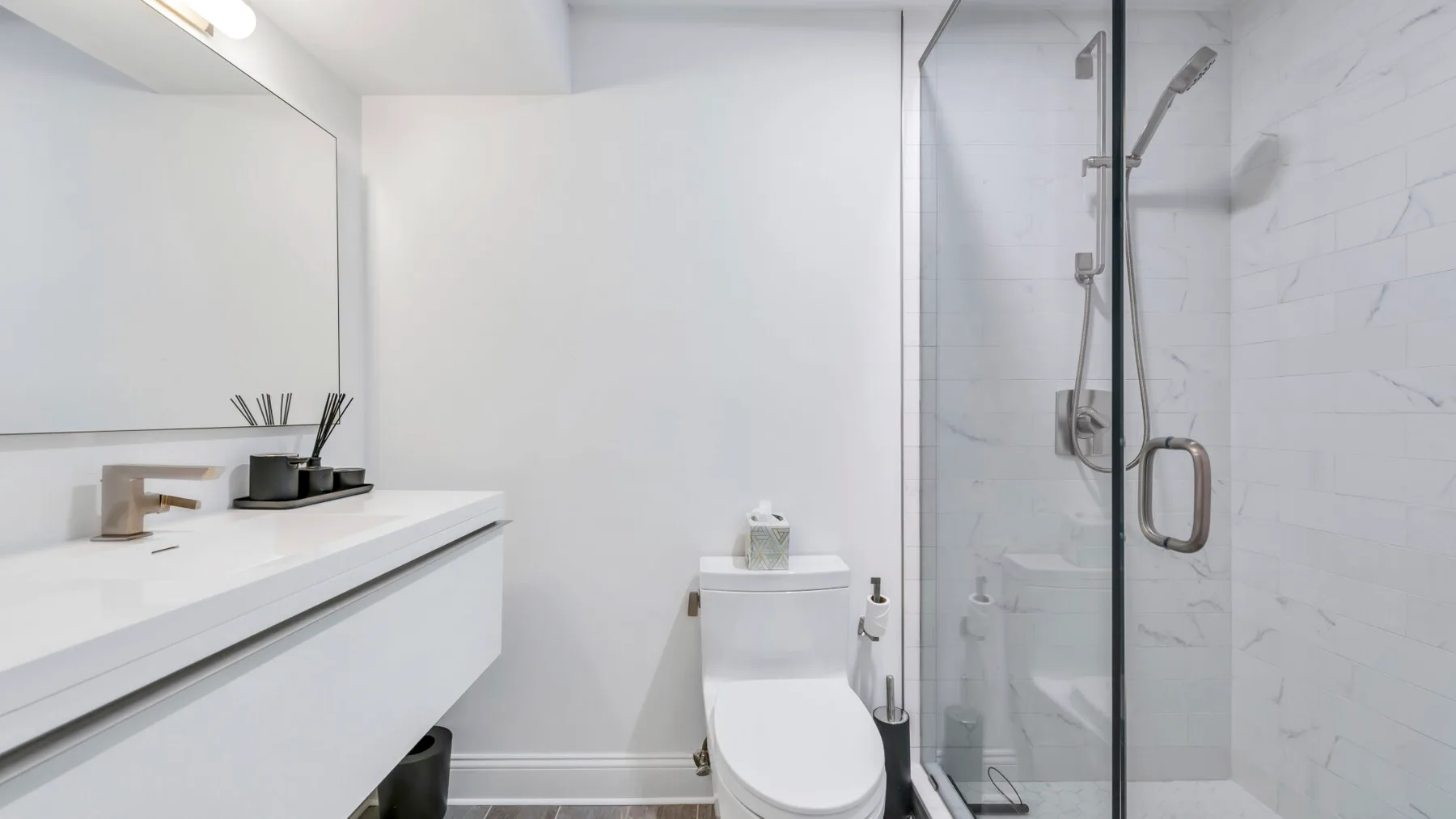 A bright bathroom with a white vanity and a glass-enclosed shower.