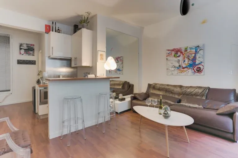 Una sala de estar y cocina de concepto abierto con una barra y asientos.