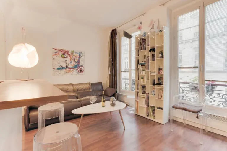 Una sala luminosa con asientos, una mesa baja y ventanas altas.