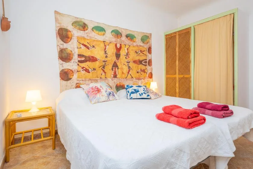 Un dormitorio con una cama grande, un tapiz colorido y toallas dobladas.