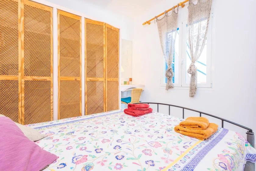 Un dormitorio con una colcha estampada, paneles tejidos y una ventana con cortinas.