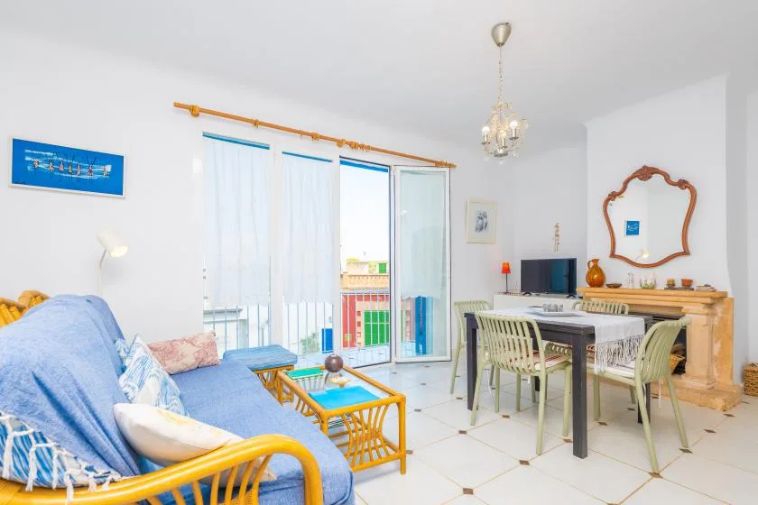 Una luminosa sala de estar y comedor con asientos, una mesa y puertas al balcón.