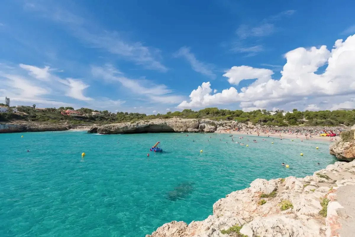 Una cala rocosa con agua turquesa y una playa de arena.