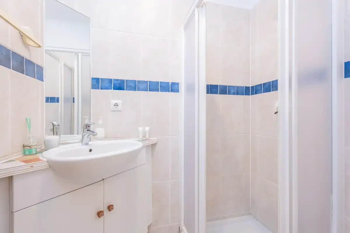 Un baño con lavabo, espejo y ducha.