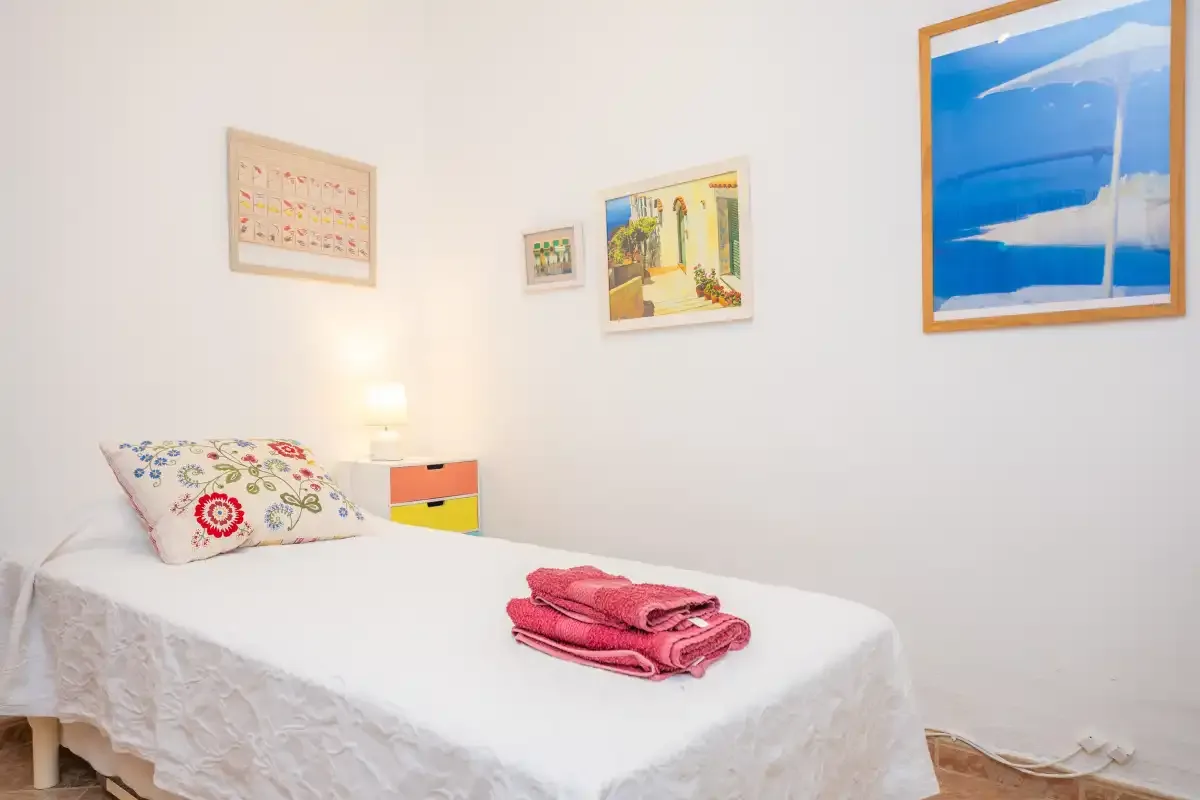 Un dormitorio con una cama, toallas dobladas y cuadros en la pared.