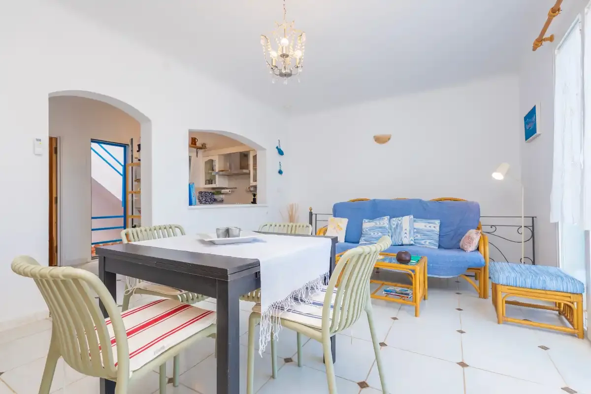Una luminosa sala de estar y comedor con un sofá azul y una mesa de comedor.