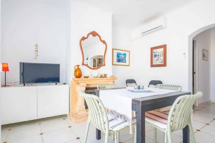 Un comedor luminoso con una mesa, sillas claras y un aparador.