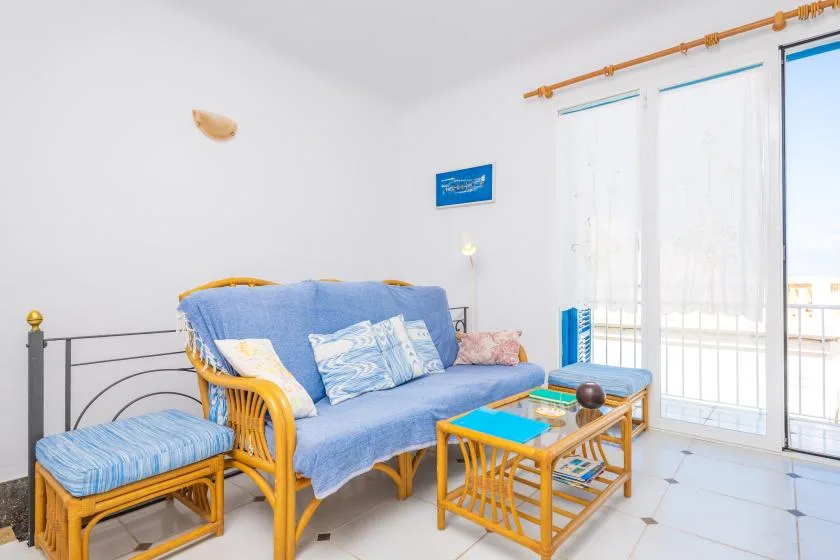 Una sala luminosa con asientos azules y ventanas altas.