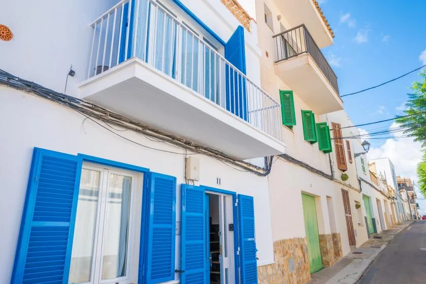 Una calle estrecha bordeada de edificios blancos y contraventanas azules.