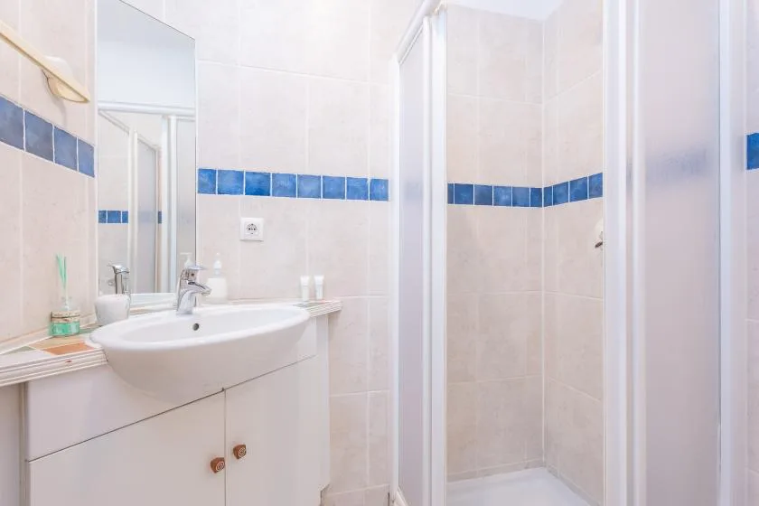 Un baño con azulejos, lavabo, espejo y ducha.