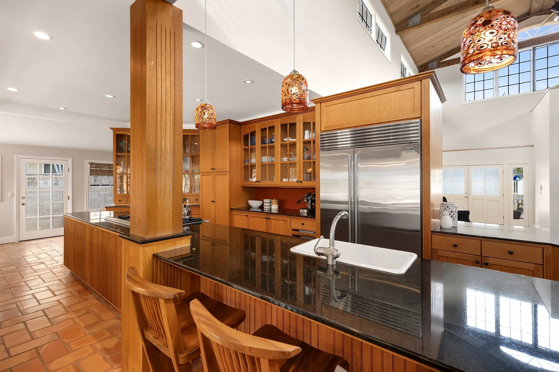 A spacious kitchen with wooden cabinetry, a central island, and pendant lights.