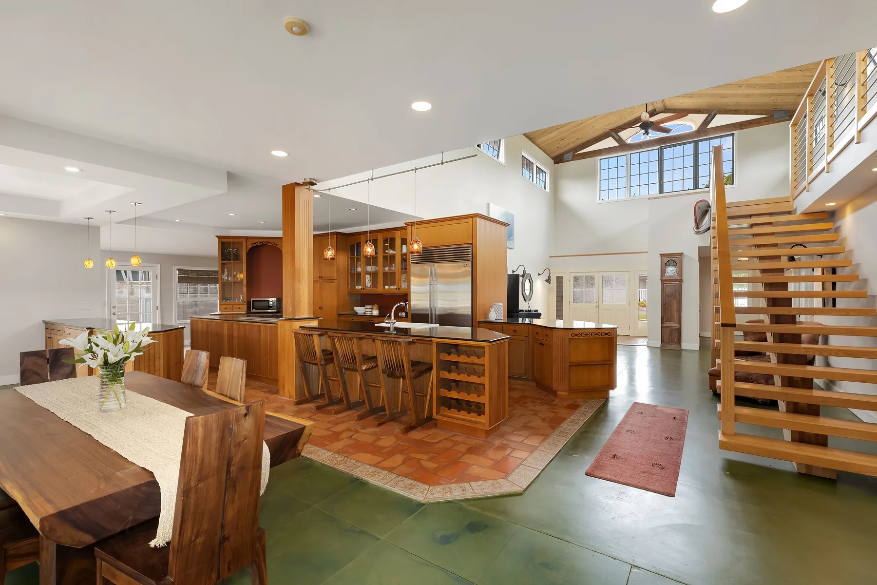 An open-plan dining and kitchen area with a long wooden table and bar seating.