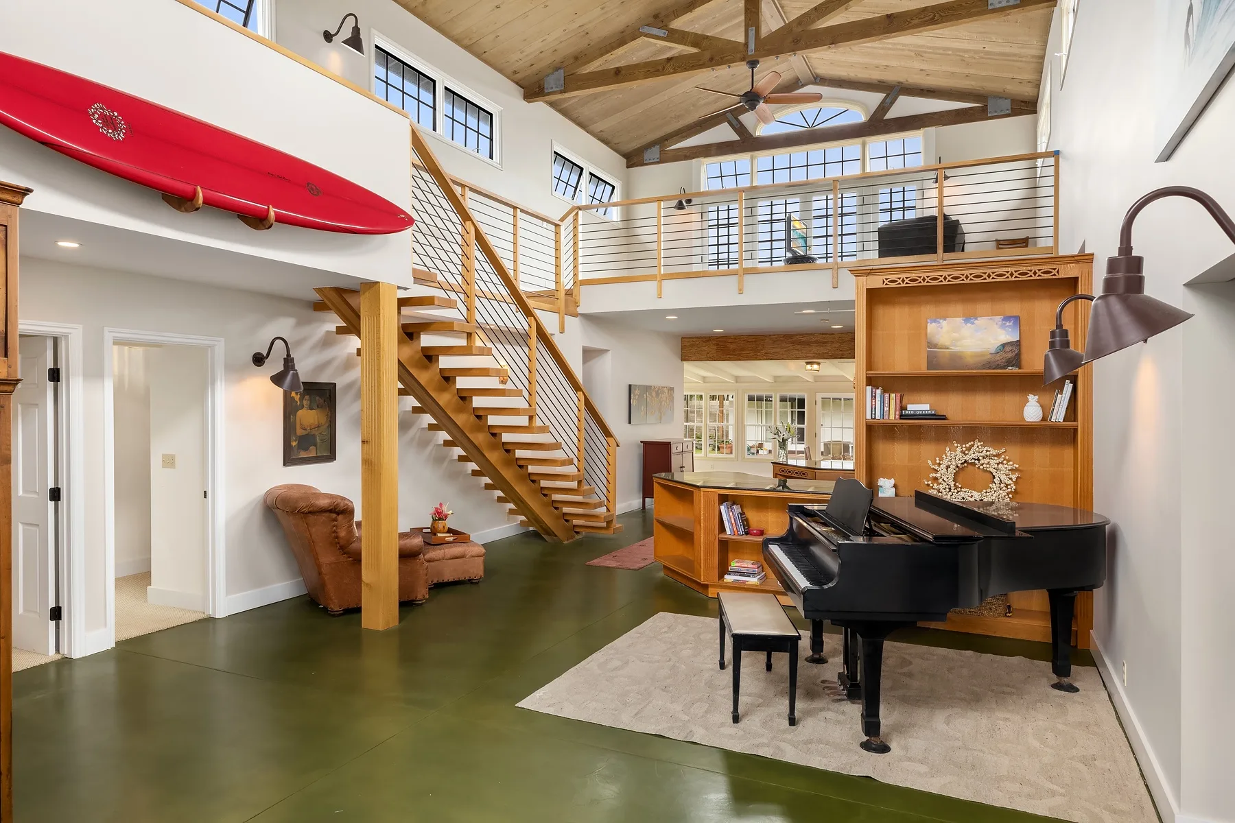 A double-height living space with a grand piano beneath a wooden staircase.
