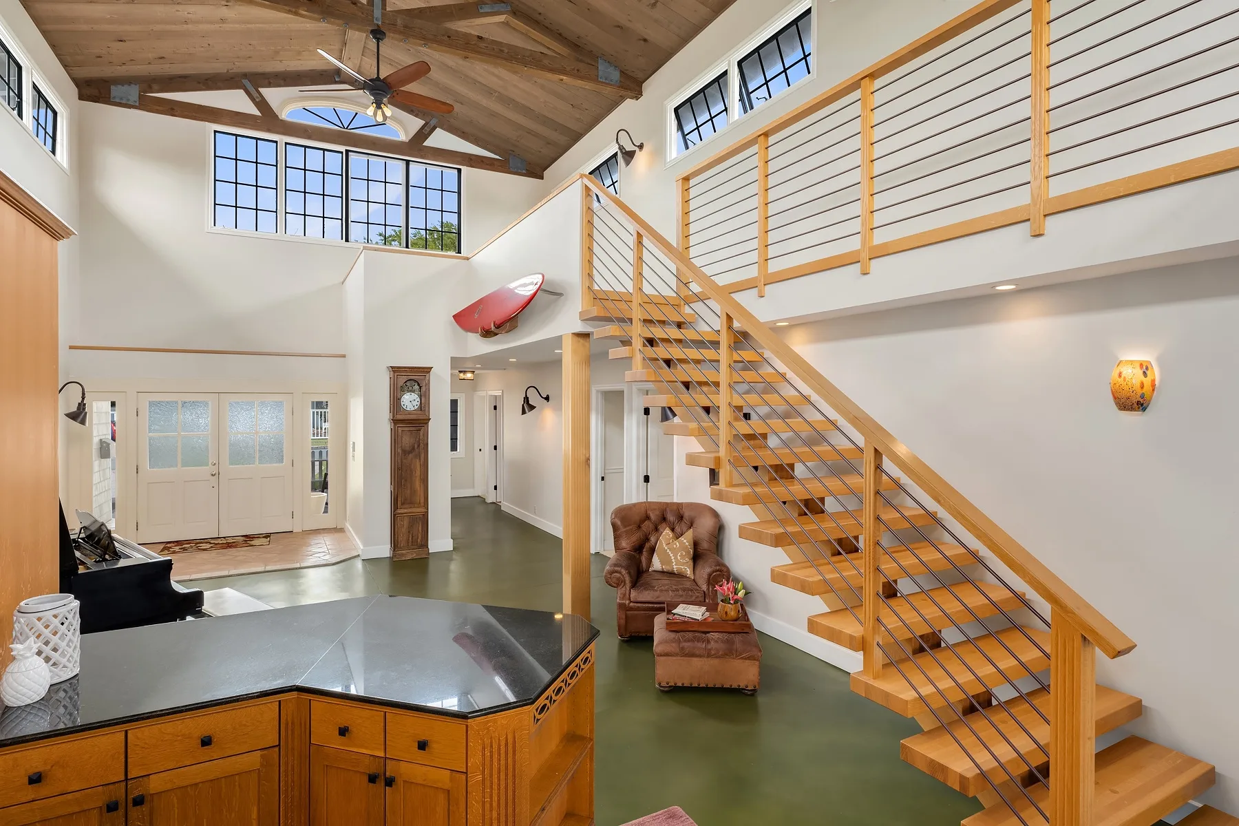 A bright open living area features a wooden staircase and a high timber ceiling.