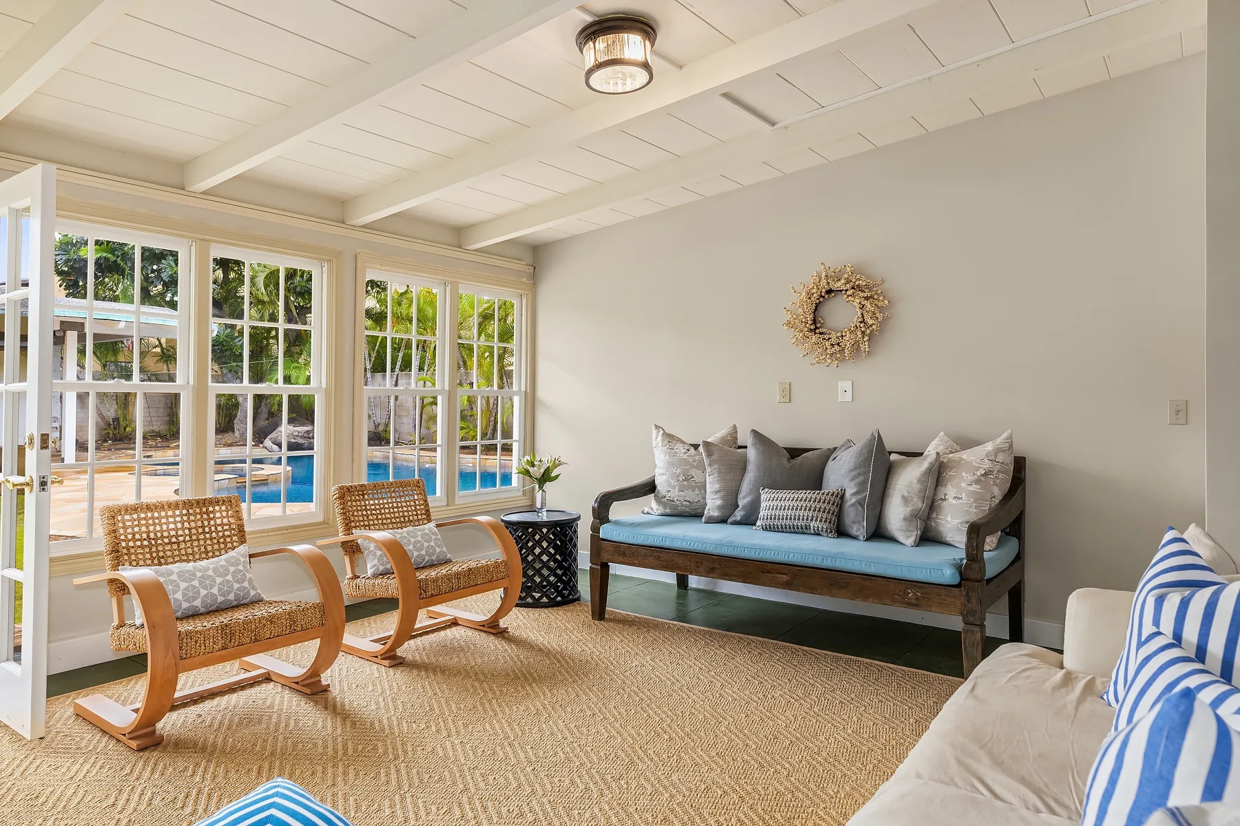 A bright sunroom with cushioned seating beside large windows overlooking a pool.