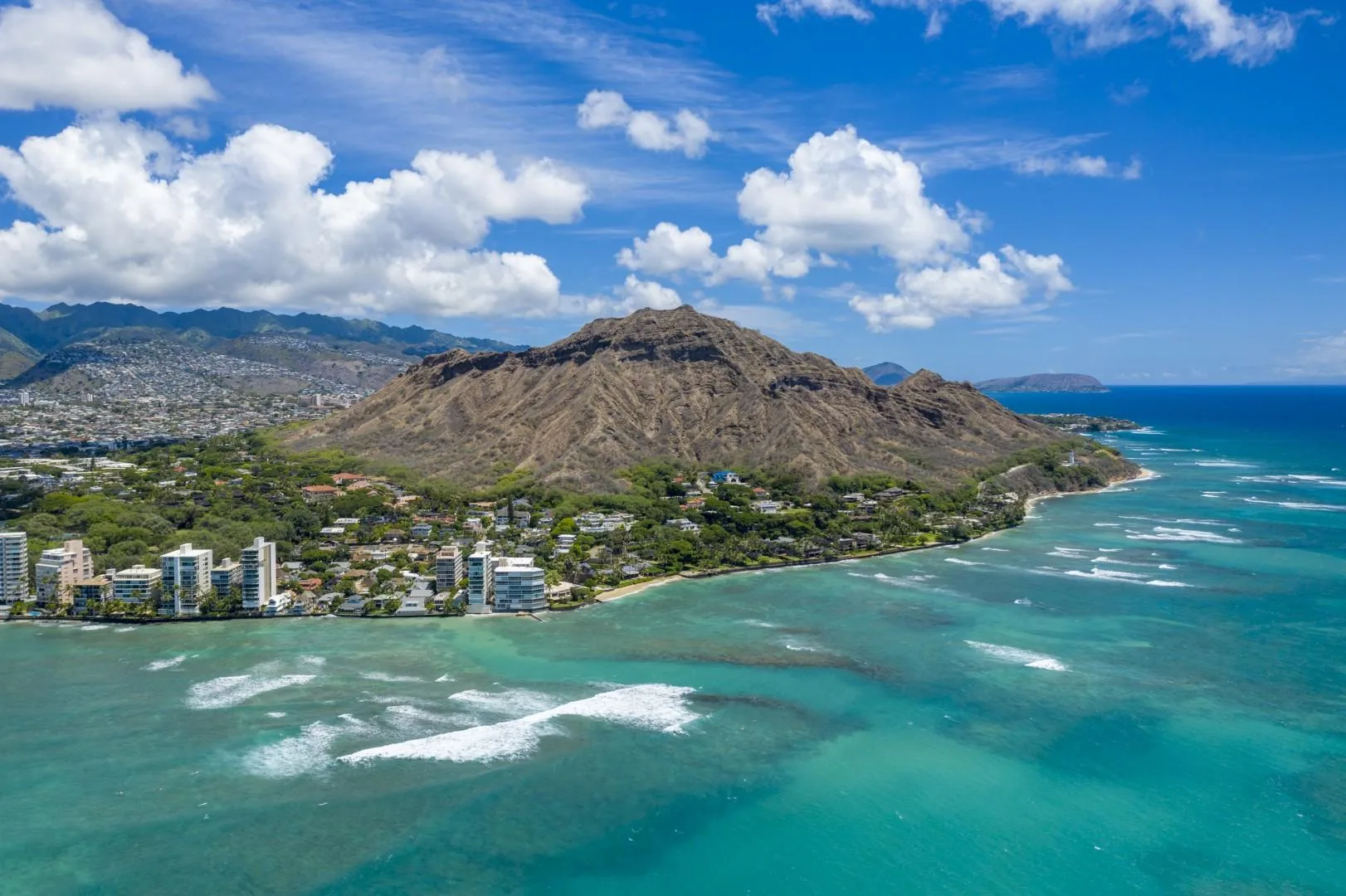 A coastal mountain rises above a developed shoreline and turquoise ocean.