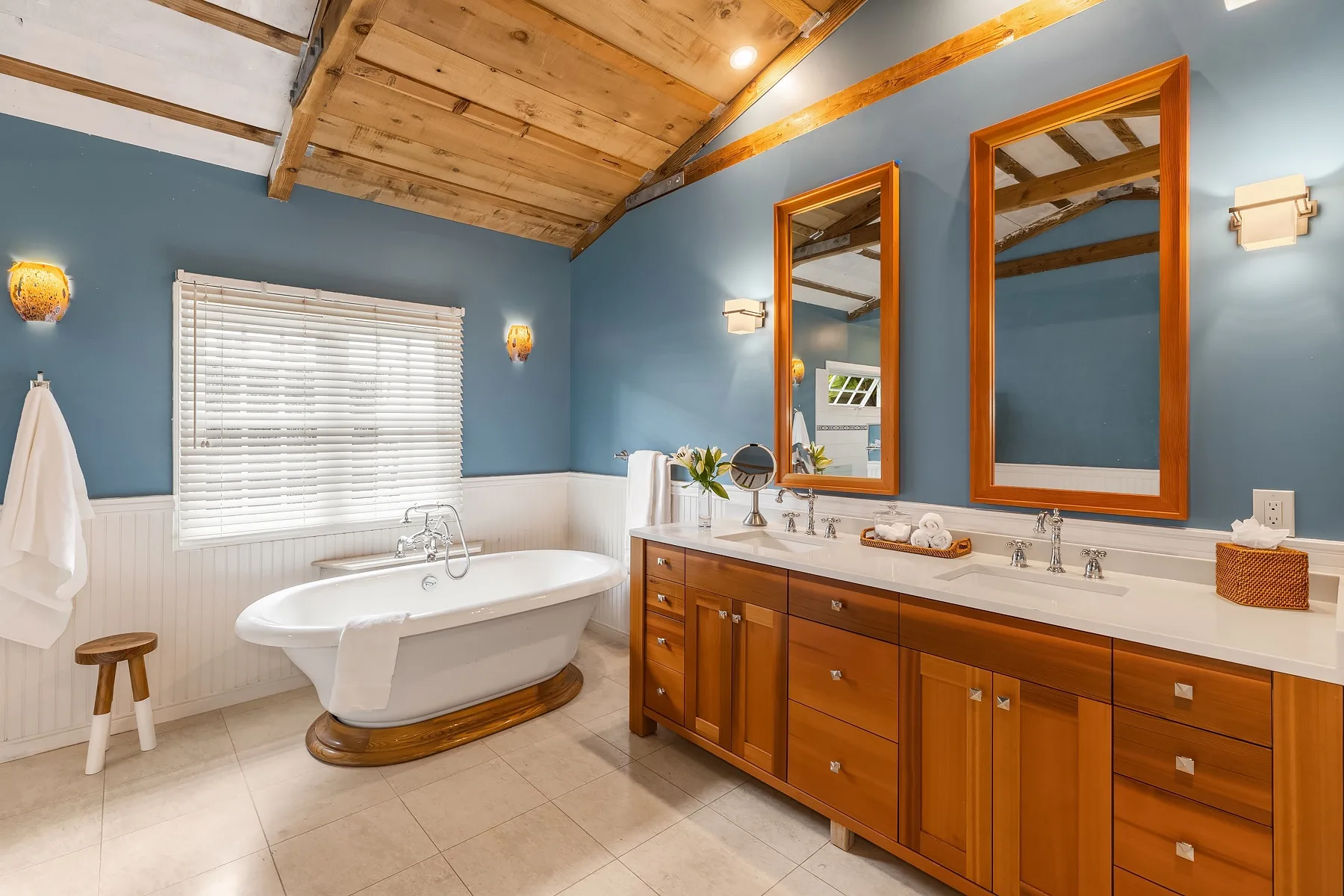 A bathroom with a freestanding bathtub and a long vanity beneath two mirrors.