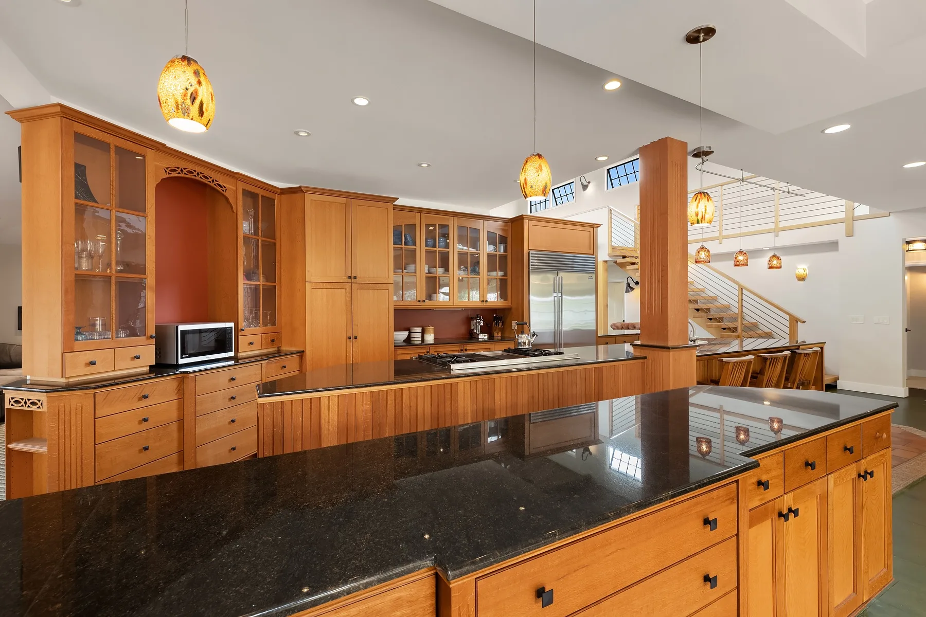 A spacious kitchen features wooden cabinetry, dark countertops, and pendant lights.