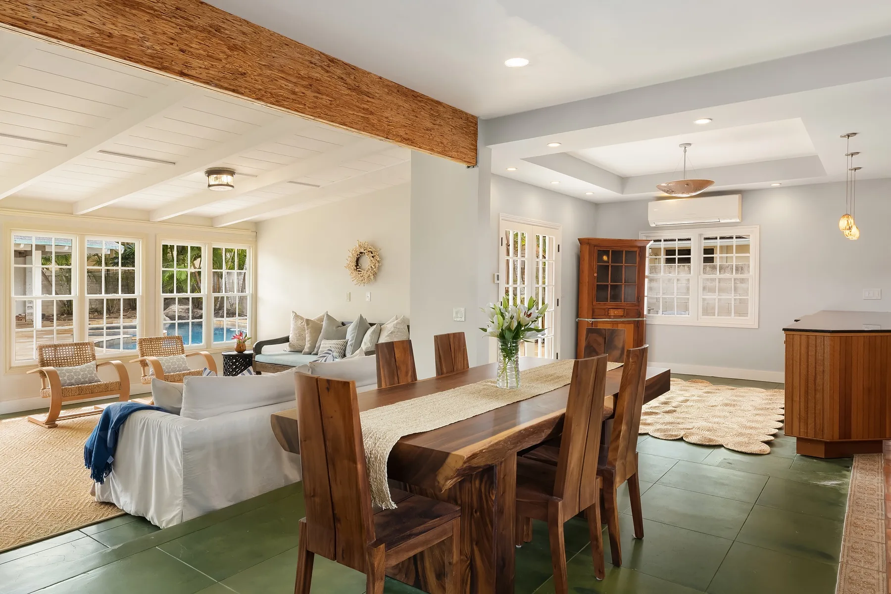 A bright open-plan living and dining room with a long wooden dining table.