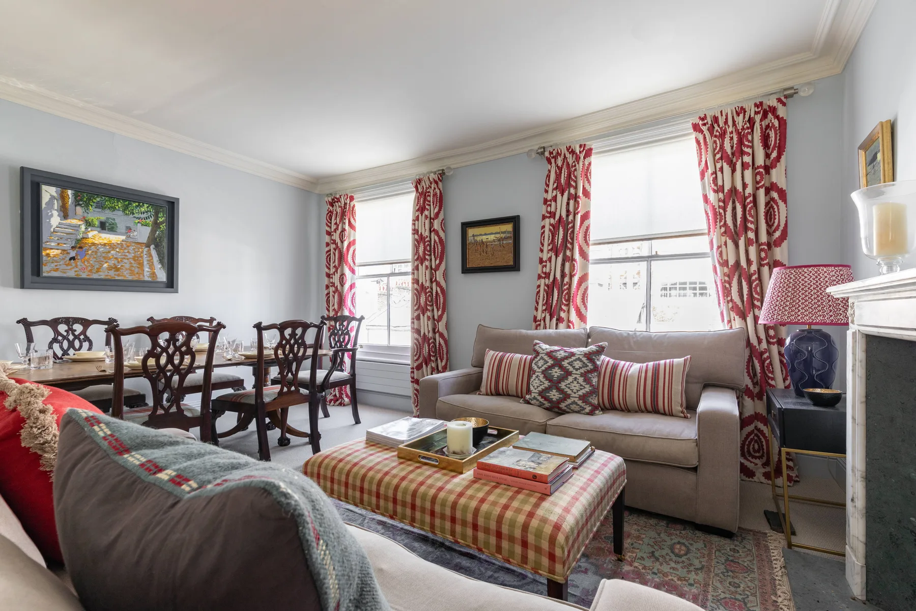 Una sala amueblada con un sofá, cortinas estampadas y una mesa de comedor.