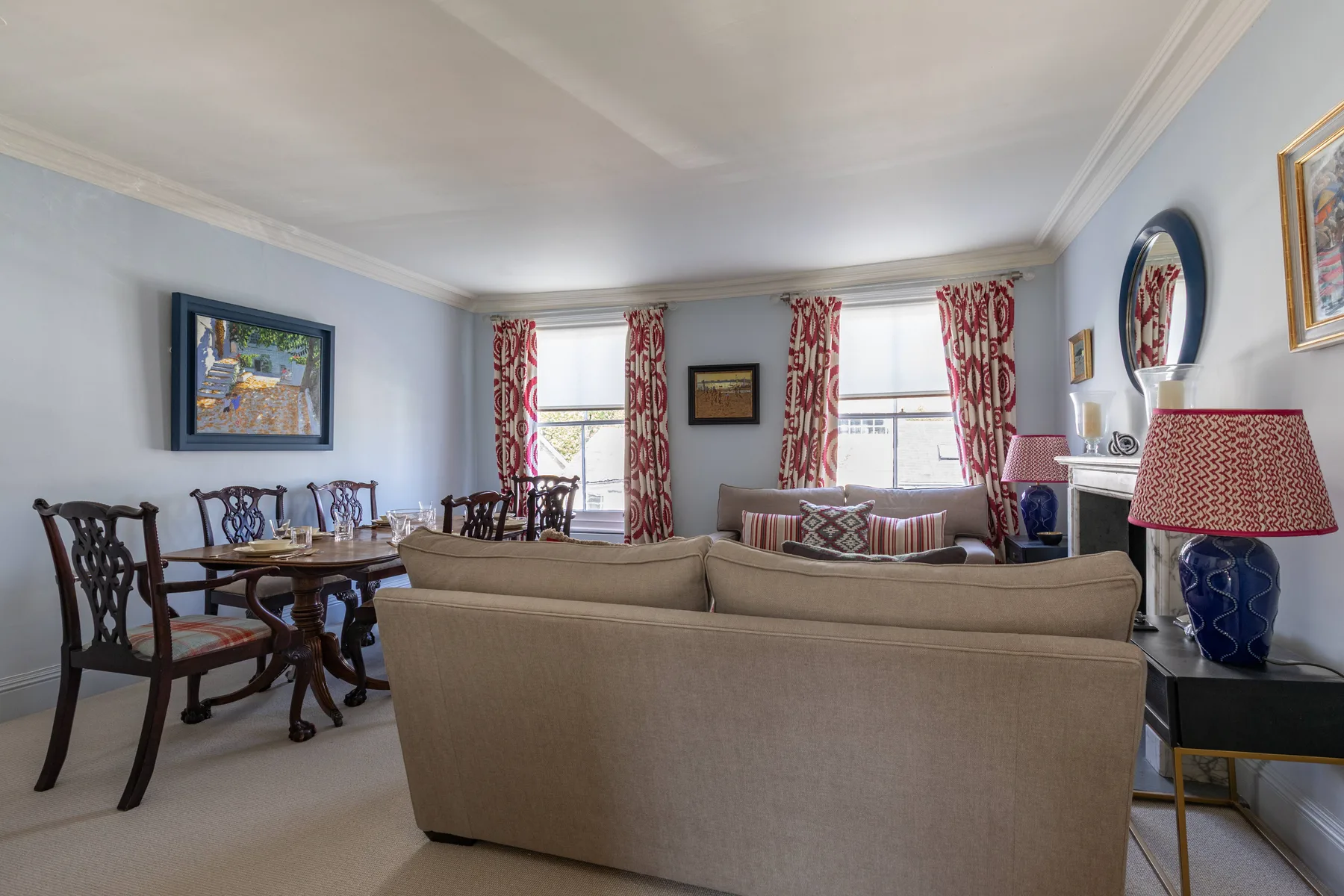 A living room with seating, a dining table, and curtained windows.