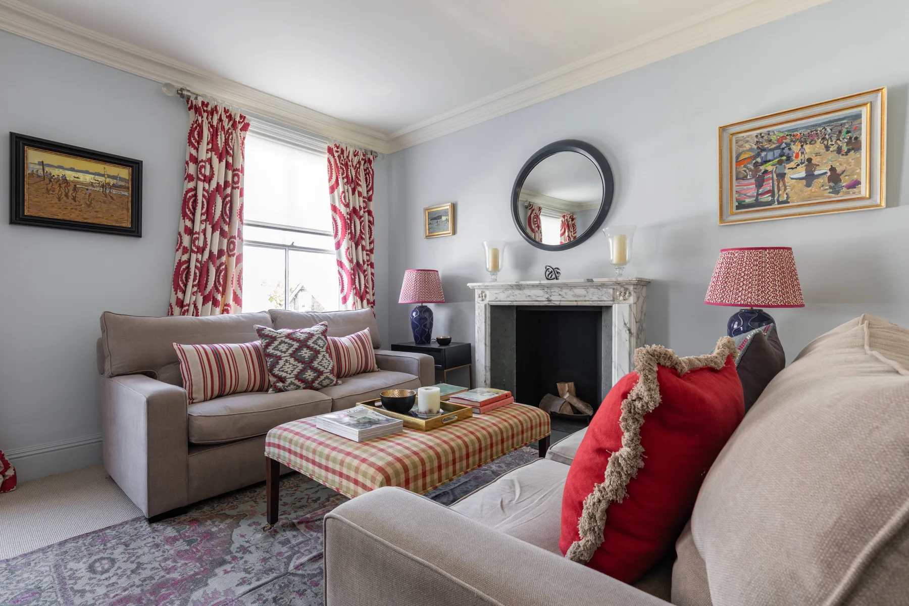 A living room with upholstered seating, a patterned ottoman, and a fireplace.