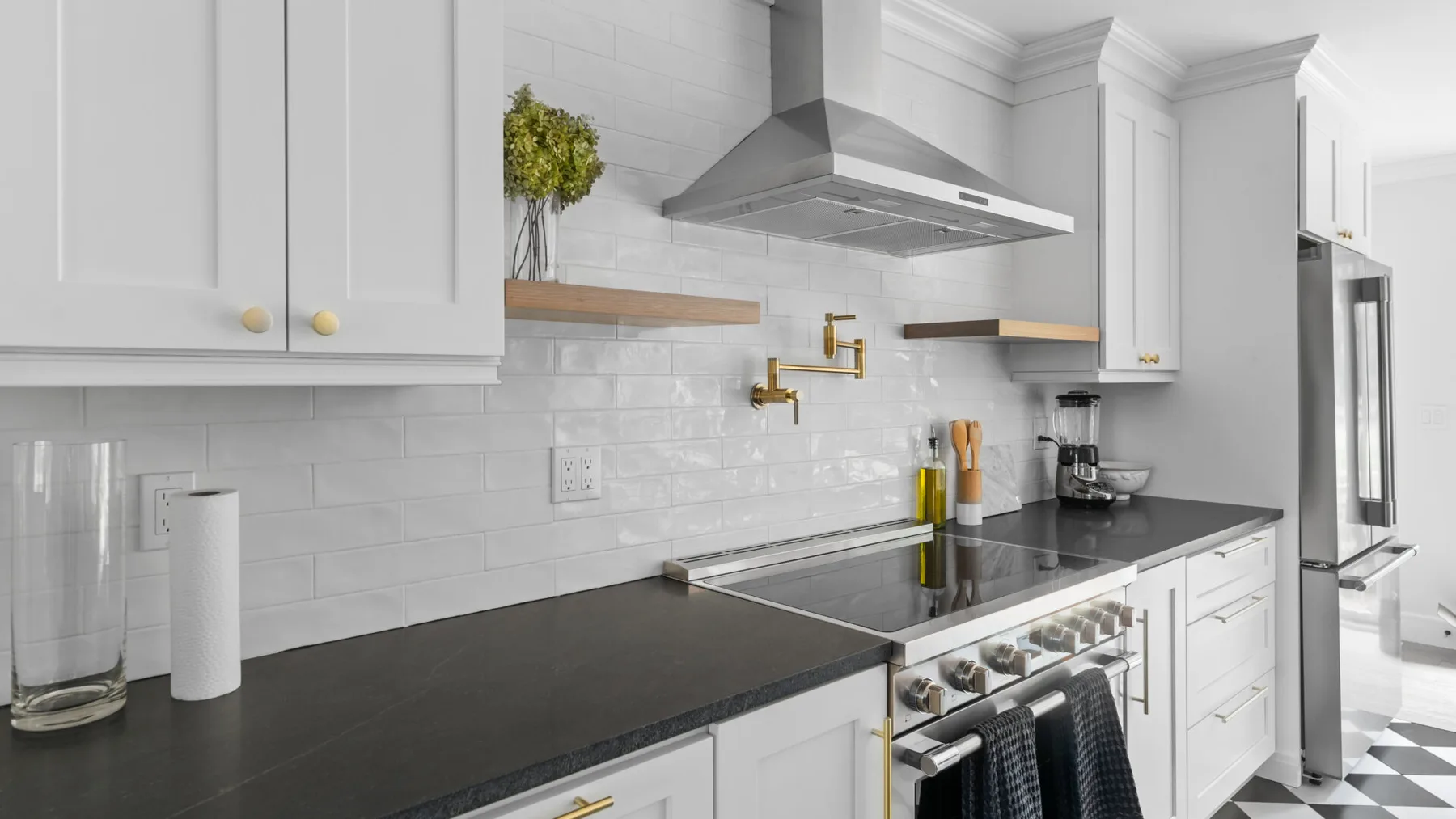 A bright kitchen with white cabinetry, dark countertops, and a stainless steel range.
