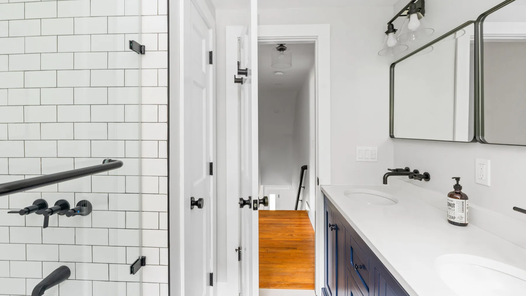 A bathroom with a white vanity, mirror, and tiled shower.