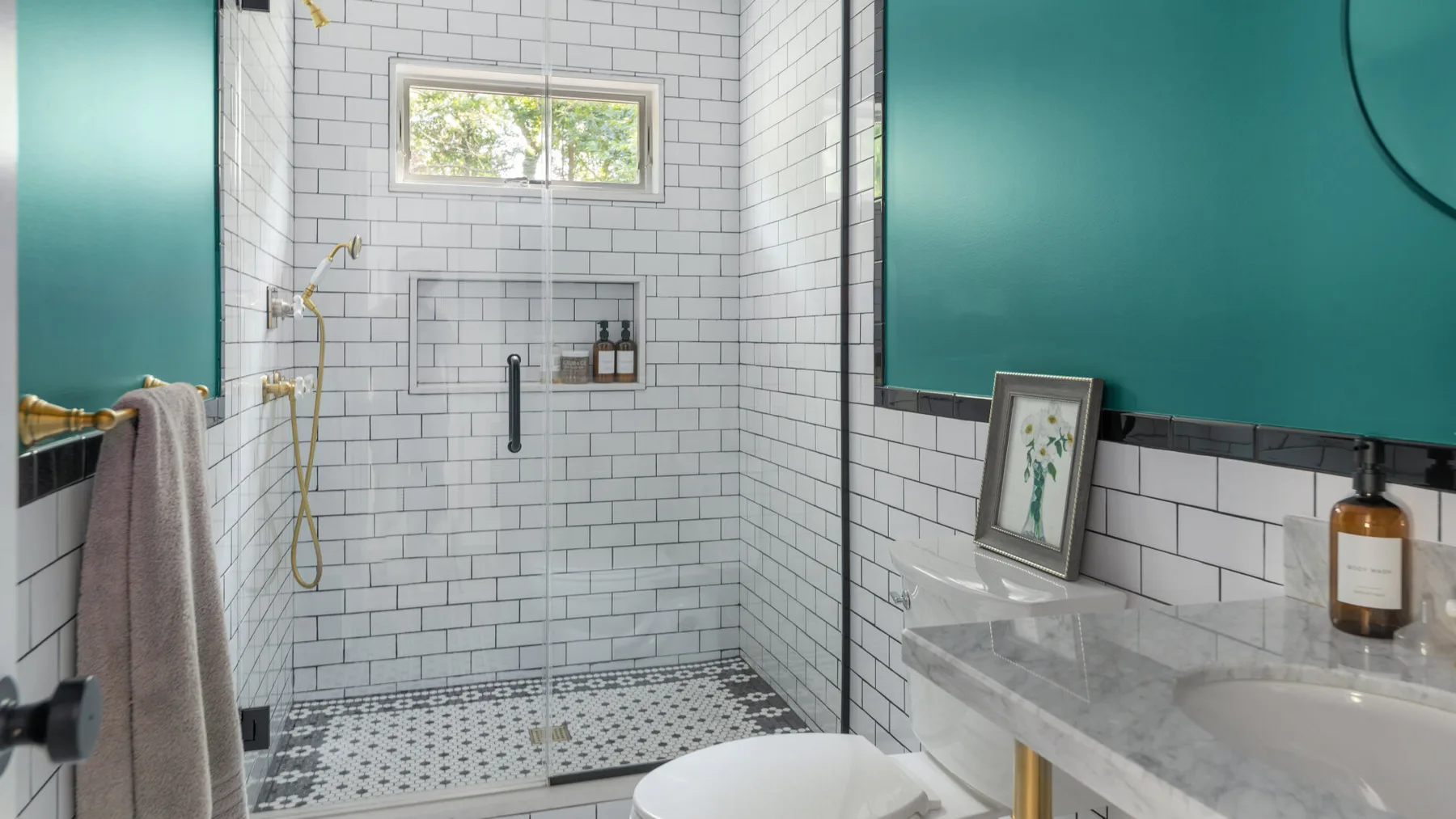 A tiled bathroom with a walk-in shower and a marble vanity.