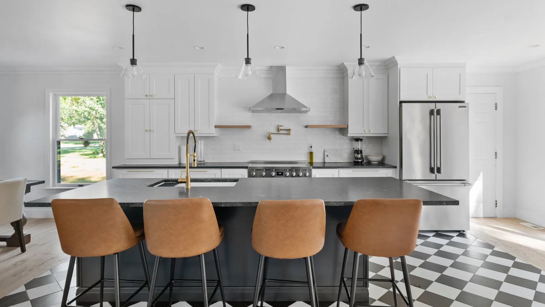 A bright kitchen with white cabinetry and a central island lined with stools.