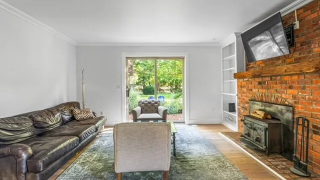 A living room with seating, a fireplace, and a window overlooking greenery.