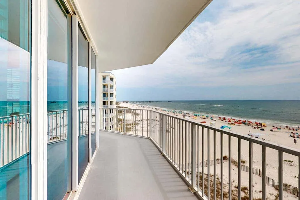 A balcony overlooks a sandy beach and the ocean.