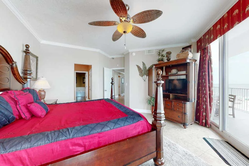 A bedroom with a bright pink bed beside a sliding glass door.