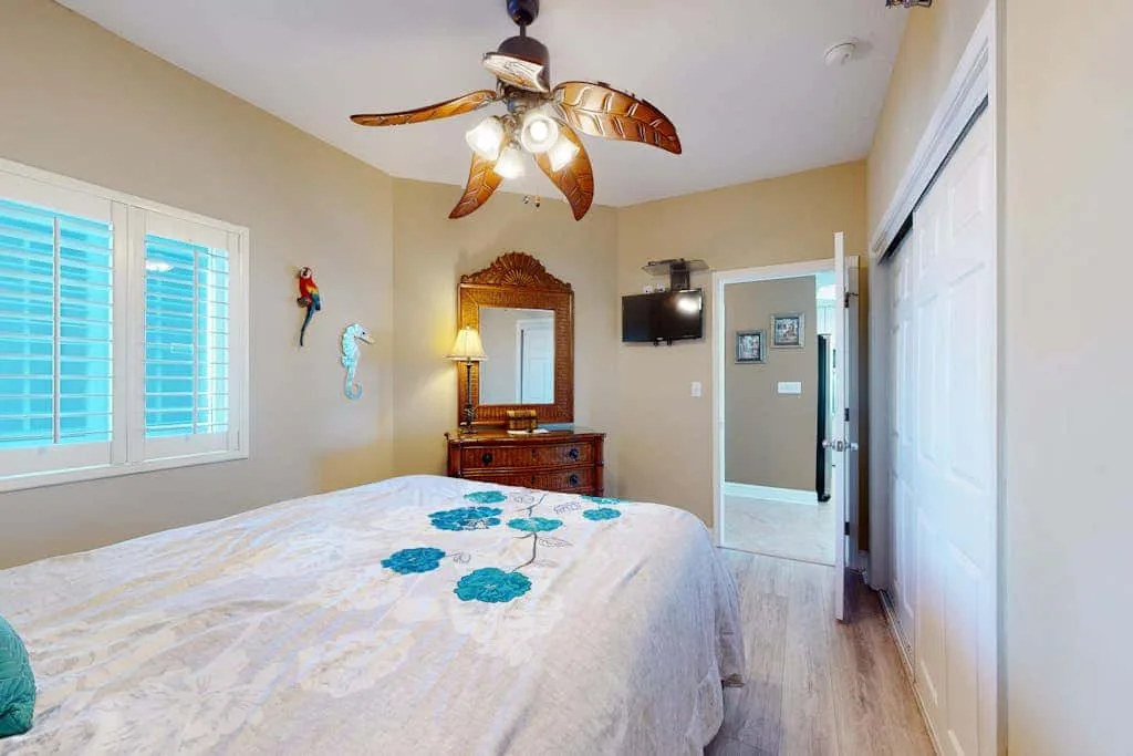 A bedroom with a bed, a window, and a ceiling fan.