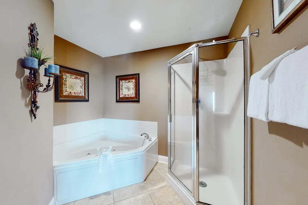 A bathroom with a corner bathtub and glass shower enclosure.