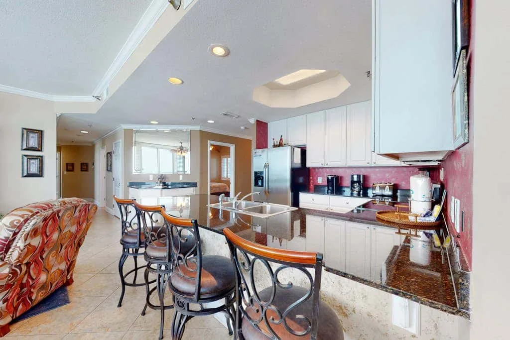 A spacious kitchen with a dark stone countertop and a row of bar seating.