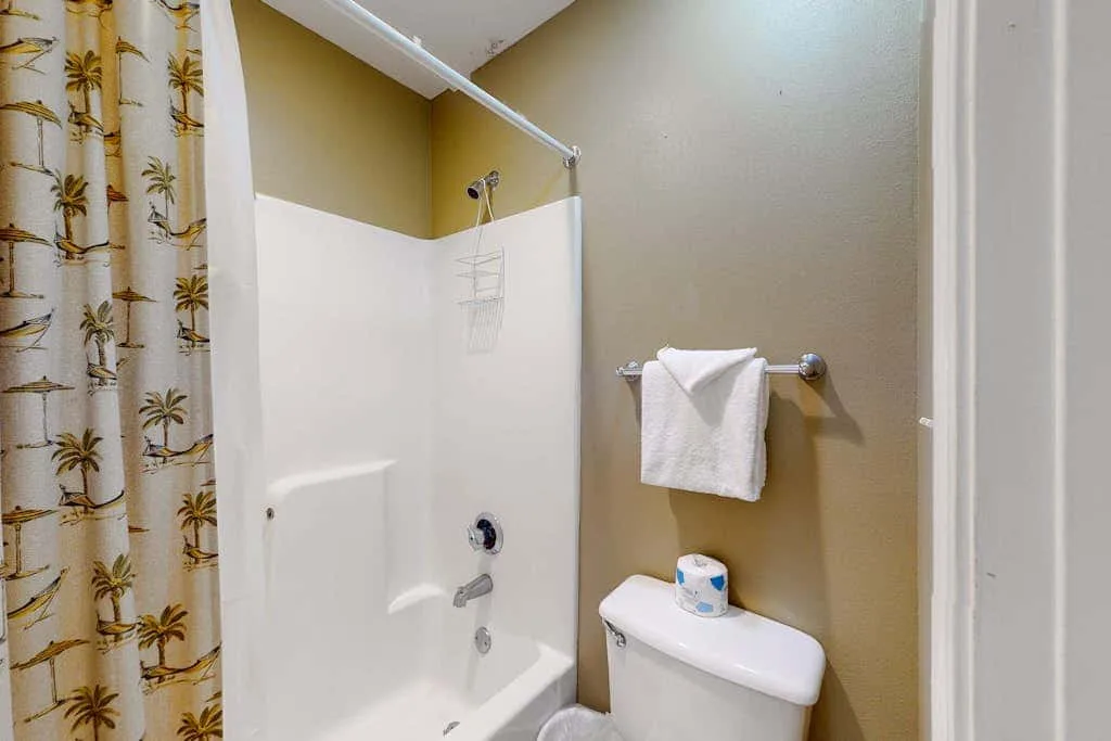 A bathroom with a shower, toilet, and towel rack.