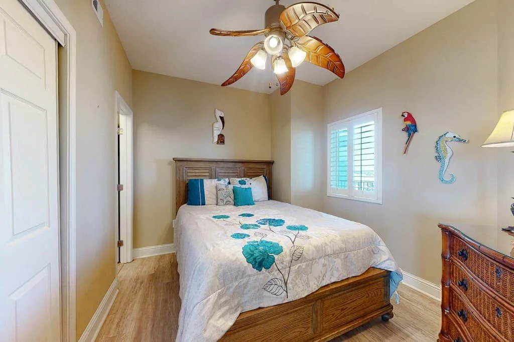 A bedroom with a wooden bed, patterned bedding, and a window with shutters.