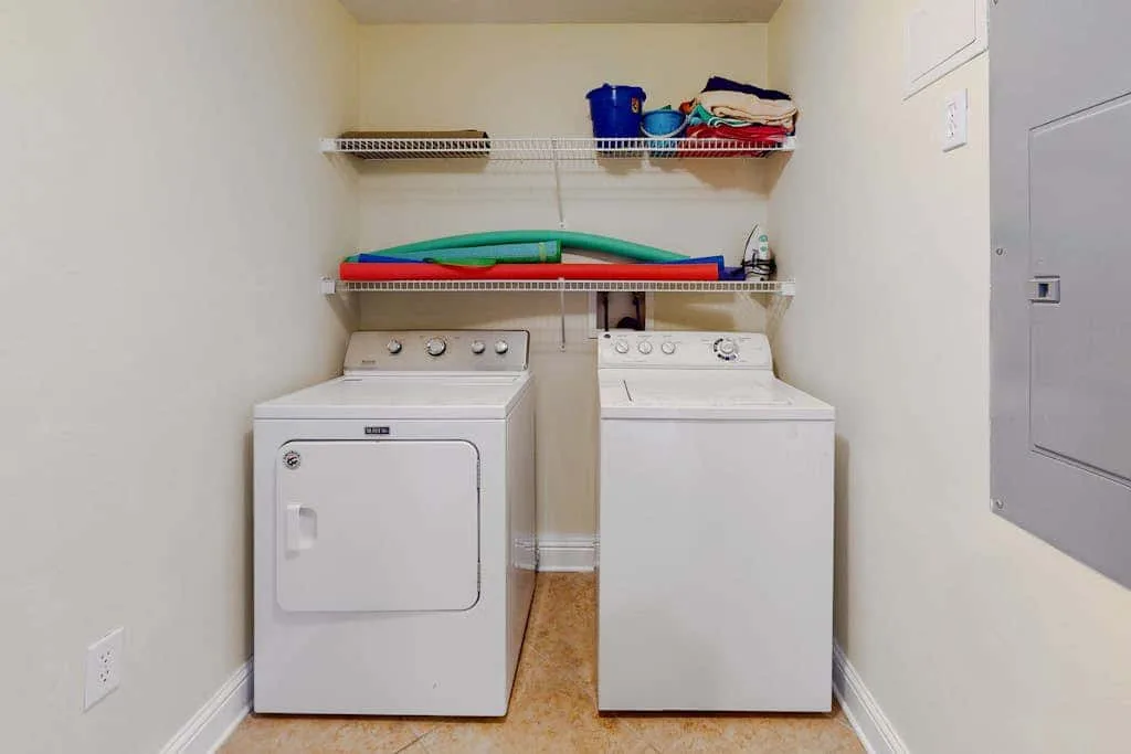A laundry room with a washer and dryer beneath wall-mounted shelves.