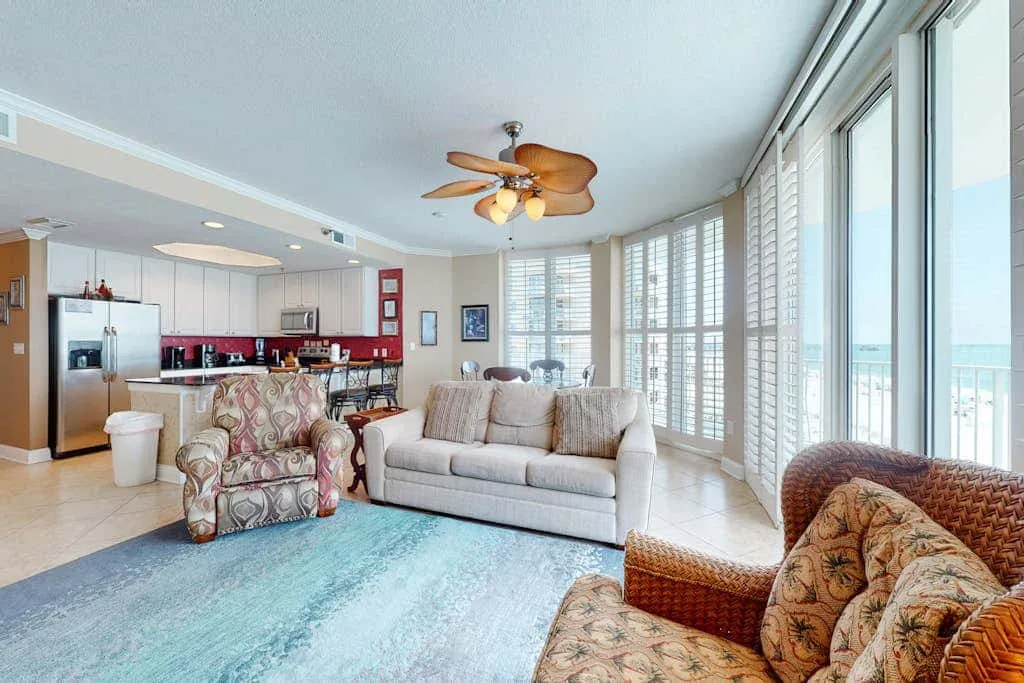 A bright living room with seating beside large windows overlooking the water.